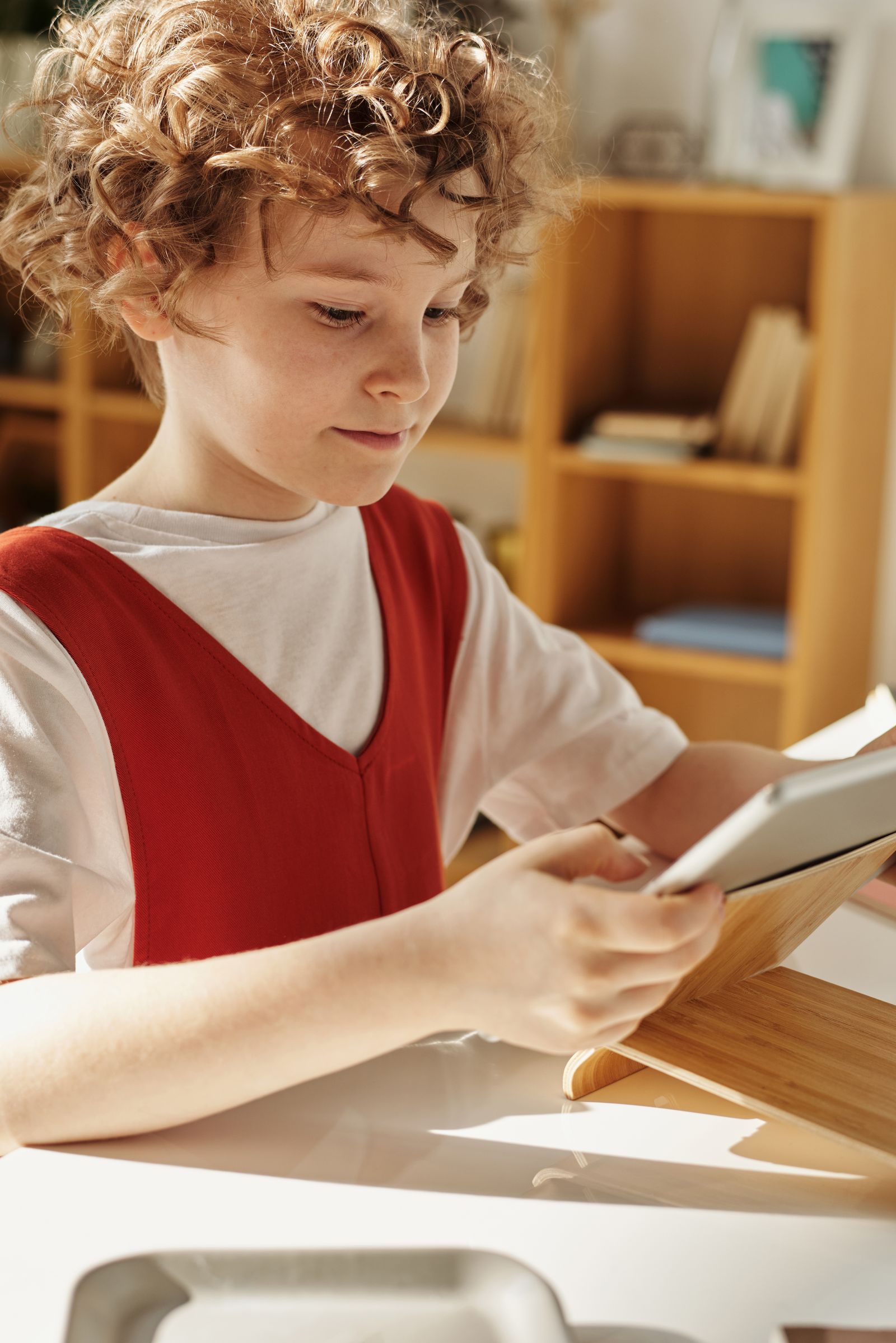 A boy reading a story on a tablet at his desk